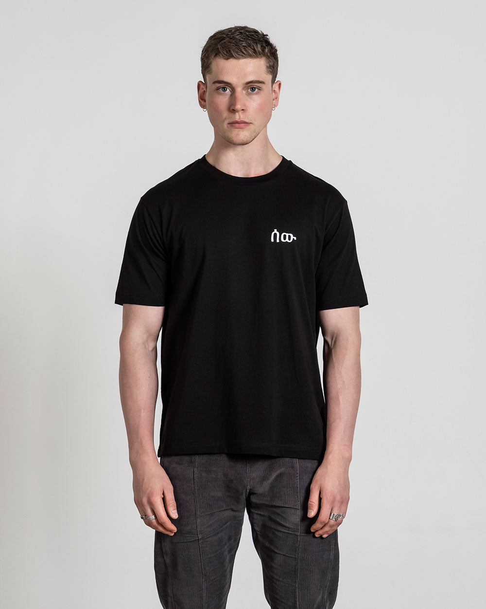 Schwarzes T-Shirt mit weißem Logo auf der linken Brust, frontal getragen fotografiert.