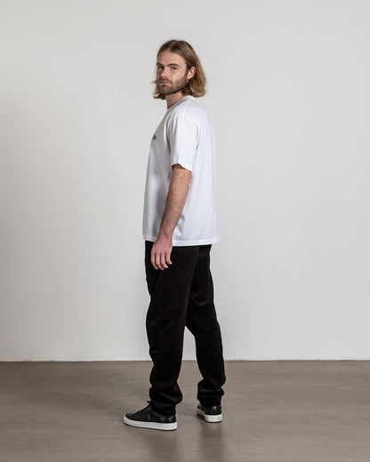 Weißes T-Shirt mit Frontprint, seitliche Ansicht eines stehenden Models mit Blick zur Kamera.